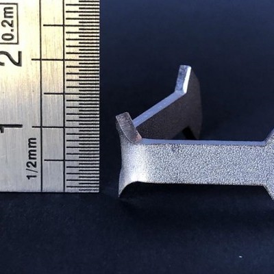 Peça metálica cinzenta ao lado de régua metálica com marcações em milímetros