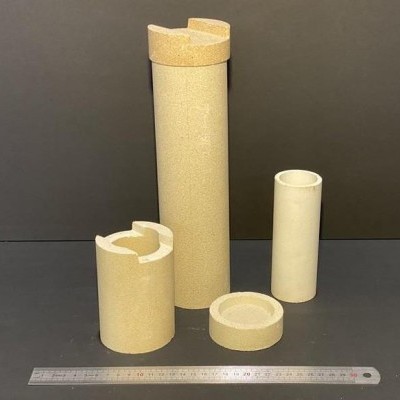 Peças cilíndricas isolantes amarelas e brancas com régua metálica à frente em fundo castanho