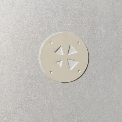 Disco redondo branco com furos e recortes triangulares sobre fundo cinzento