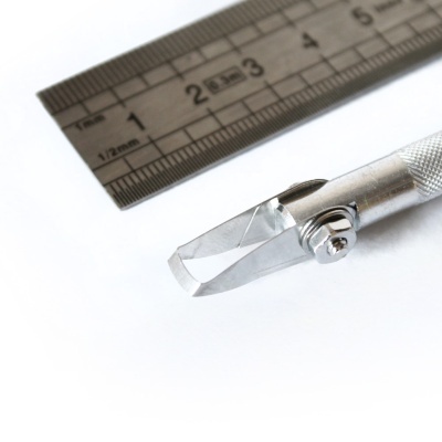 Cortador de precisão metálico junto a régua metálica com marcações em cm e mm