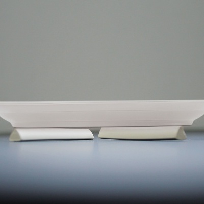 Prato branco oval de cerâmica sobre superfície azul-clara