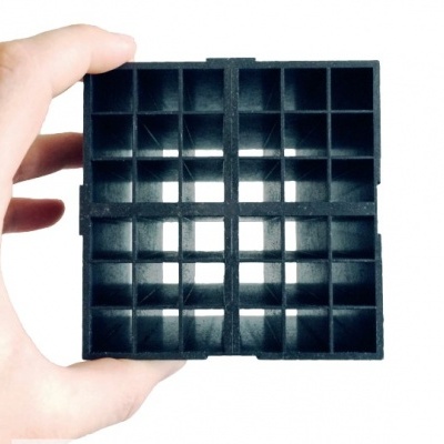 Bloco preto quadrado com múltiplas cavidades, segurado por mão, fundo branco