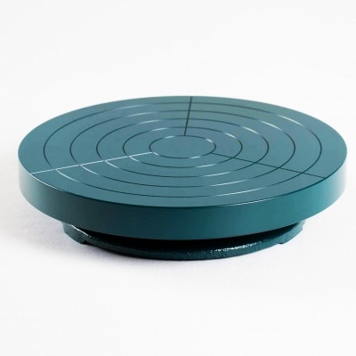 Prato giratório verde de metal com sulcos circulares.