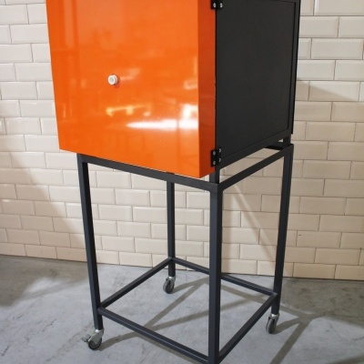 Armário metálico laranja com suporte de estrutura metálica preta e rodas