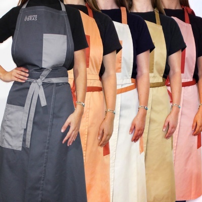 Cinco aventais coloridos usados por pessoas em linha com camisetas pretas