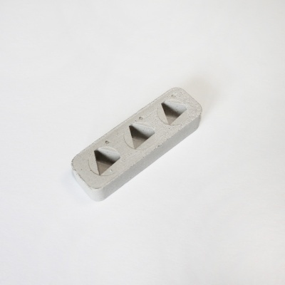 bloco de cimento cinzento claro com três cavidades em forma de pirâmide