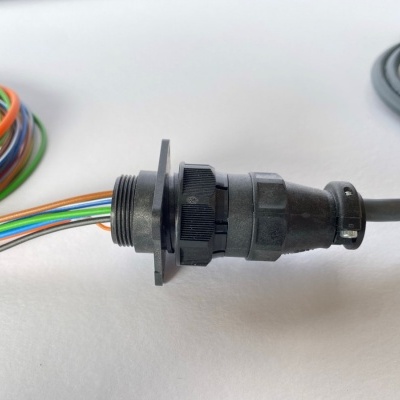Conector industrial preto com cabos coloridos e cinzentos sobre fundo branco