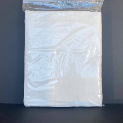 Pacote com tecido branco embalado em plástico transparente sobre fundo escuro