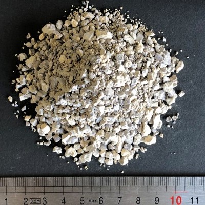 Fragmentos irregulares bege e brancos sobre superfície preta com régua de metal embaixo