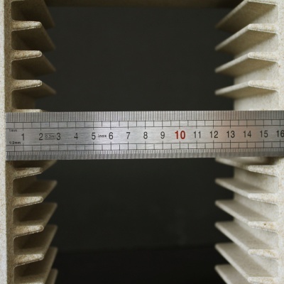 Objeto cinza rugoso com aletas verticais e régua metálica horizontal