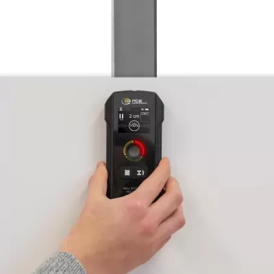 Detector de paredes preto com display digital e luzes coloridas em superfície branca