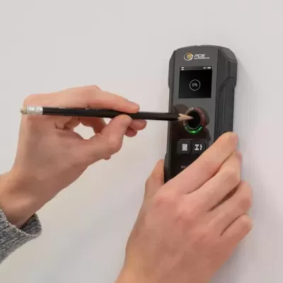 Detector digital PCE Instruments preto com ecrã e marcando parede com lápis
