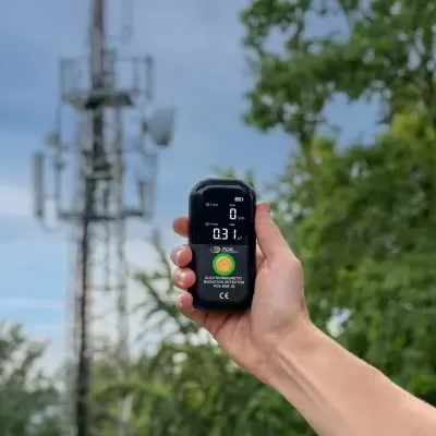 Detetor de radiação electromagnética preto com ecrã digital e botão amarelo ao ar livre