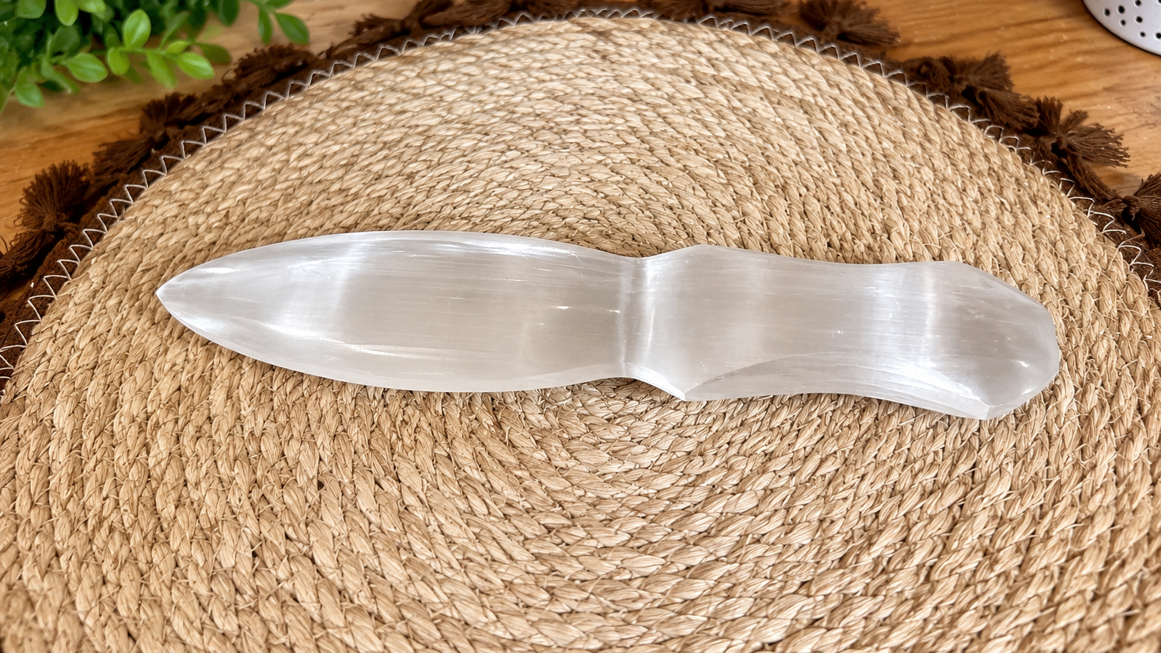 Adaga Selenite 20cm Espátula em selenite branca translúcida sobre tapete trançado