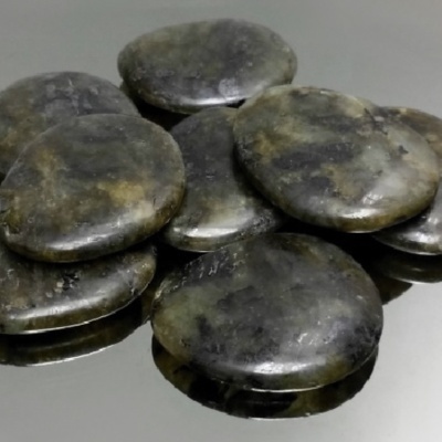 Pedras polidas verdes escuras e pretas sobre superfície preta refletora