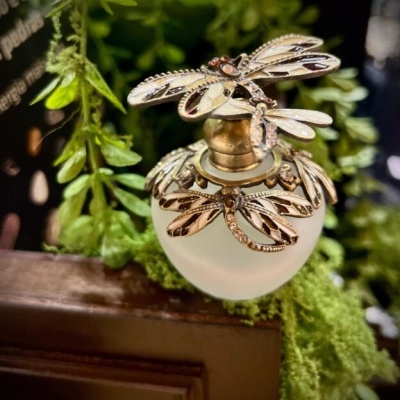 Frasco de perfume opaco com tampa decorada com libélulas douradas e pedras transparentes