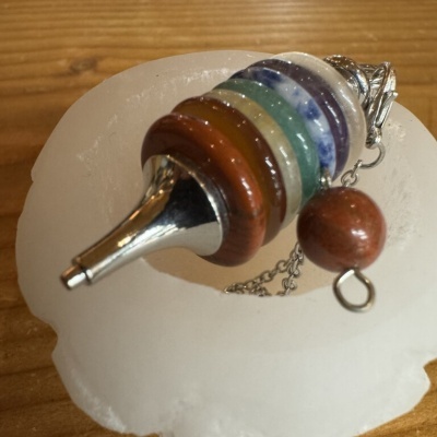 Pêndulo colorido em metal e madeira sobre superfície branca e textura de madeira