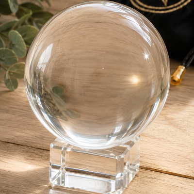 Esfera de cristal transparente sobre base cúbica em cristal sobre mesa de madeira clara
