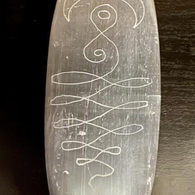 Prancha de surf translúcida com desenho branco abstrato sobre fundo escuro