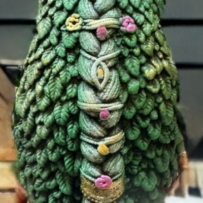 Cabelo verde tecido com ornamentos florais e detalhes dourados.