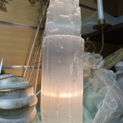 Escultura de cristal transparente com luz interior sobre tecido azul claro
