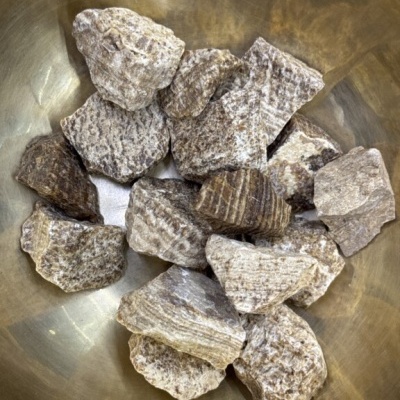 Pedras castanhas estriadas em bacia metálica dourada
