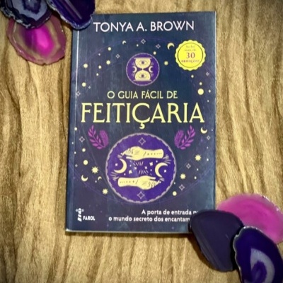 Livro O Guia Fácil de Feitiçaria de Tonya A. Brown com pedras de ágata coloridas sobre tecido dourado.