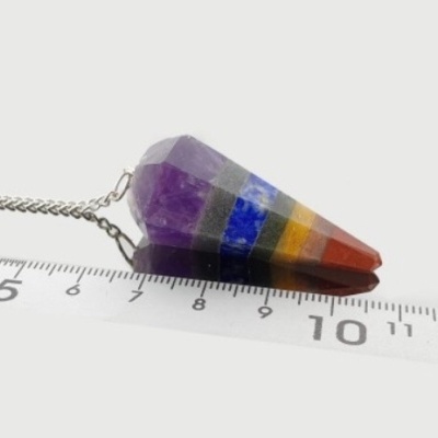 Pendulo colorido em formato cónico com corrente sobre régua transparente.