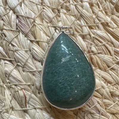 Pendente gota verde com metal prateado sobre tecido trançado