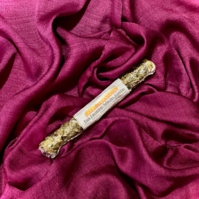 Incenso enrolado com etiqueta branca sobre tecido cor de vinho