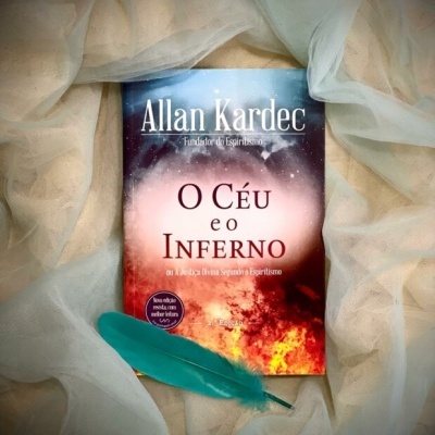 Livro O Céu e o Inferno de Allan Kardec sobre tecido transparente bege com pena azul