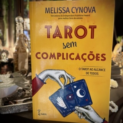Capa amarela de livro Tarot sem Complicações com ilustração de mãos e cartas de tarot