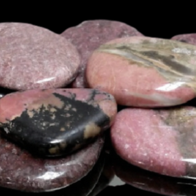 Pedras polidas cor-de-rosa com manchas pretas e cinzentas sobre fundo preto
