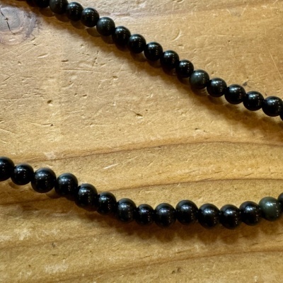 Colar ou pulseira de contas pretas sobre madeira