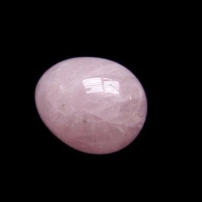 Pedra semipreciosa oval rosa polida sobre fundo preto.