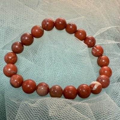 Pulseira com contas vermelhas e castanhas em tecido branco transparente
