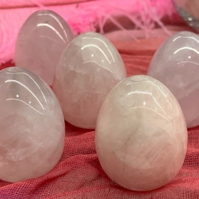 Cinco ovos de quartzo rosa polidos sobre tecido vermelho