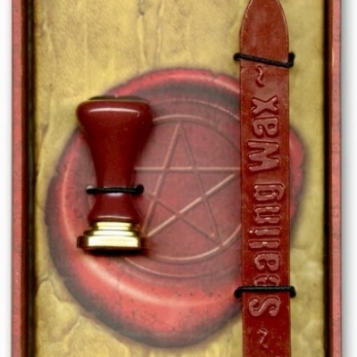 Conjunto para lacre com selo e vela vermelha em fundo decorativo com pentagrama