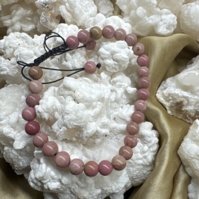 Pulseira rosa e bege sobre pedras brancas e tecido dourado