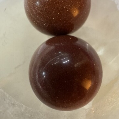 Duas esferas castanhas brilhantes num recipiente translúcido