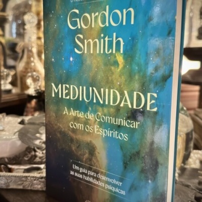 Livro Mediunidade de Gordon Smith com capa azul e verde sobre superfície de madeira