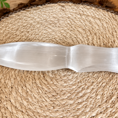 Espátula em selenite branca translúcida sobre tapete trançado
