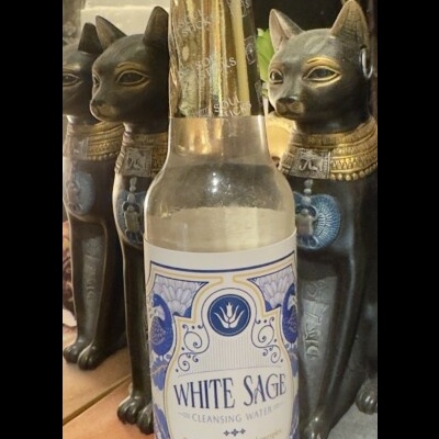 Frasco de água de limpeza White Sage com estátuas de gatos egípcios ao fundo