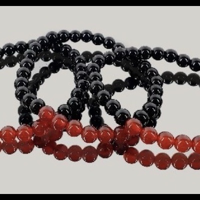 Pulseiras de contas pretas com secção vermelha sobre fundo cinza claro