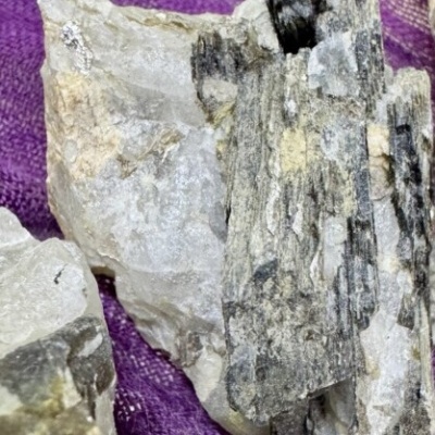 Rochas minerais cinza, branca e preta sobre tecido roxo