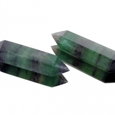 Duas pedras de cristal verdes e roxas em forma de varinha, sobre fundo branco