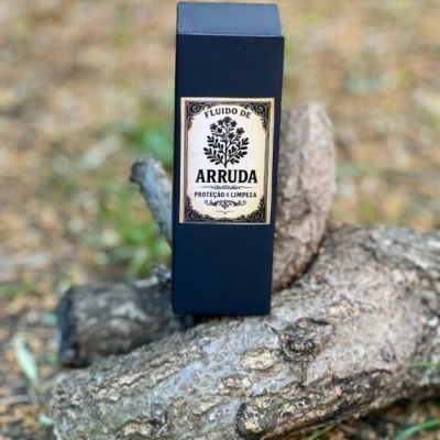Embalagem preta de fluido de arruda sobre troncos de madeira