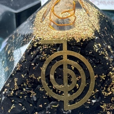 Pirâmide decorativa com símbolo geométrico dourado e elementos dentro de resina transparente