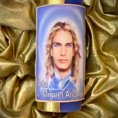 Vela azul e dourada com rótulo do Anjo São Miguel Arcanjo sobre tecido dourado.