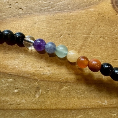 Colar ou pulseira com contas de várias cores sobre madeira clara
